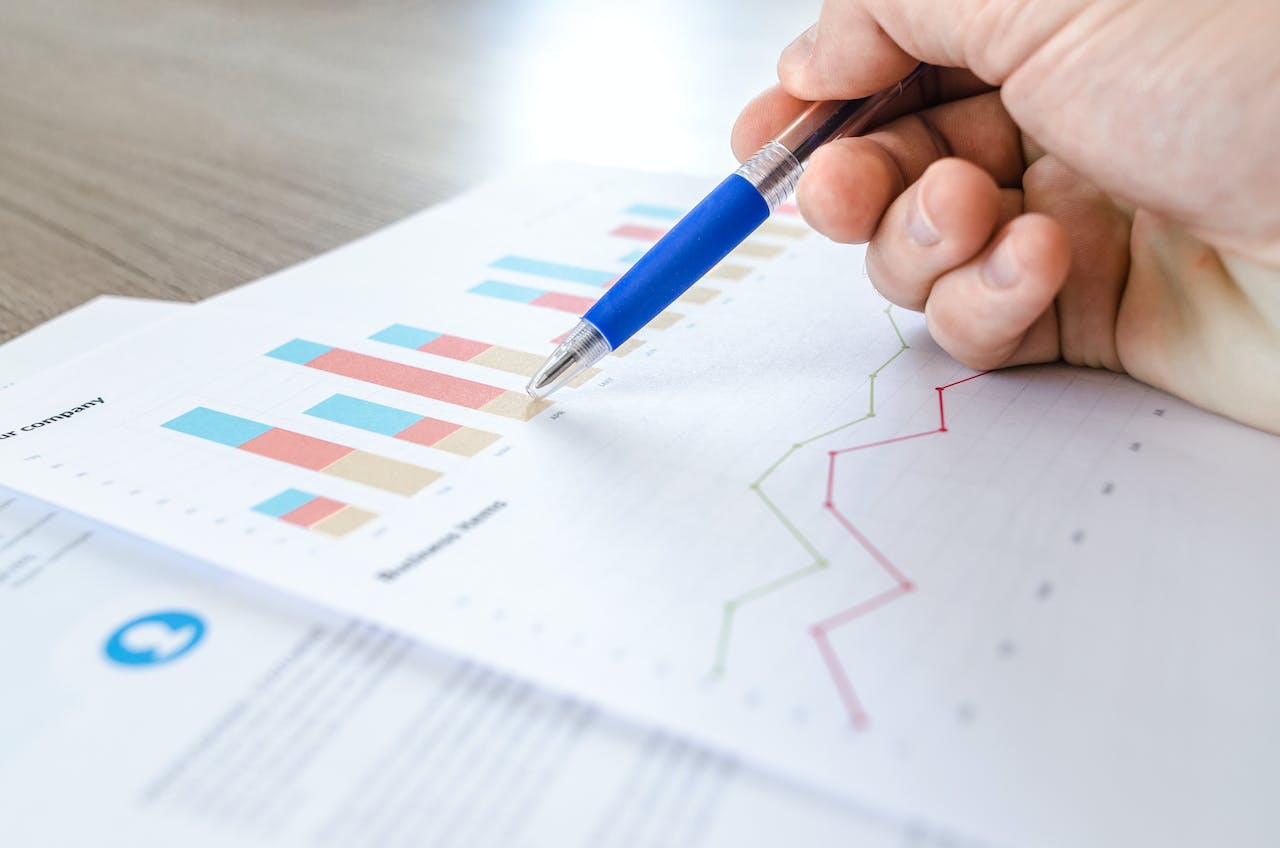 person holding pen over a paper with bar chart showing insight 