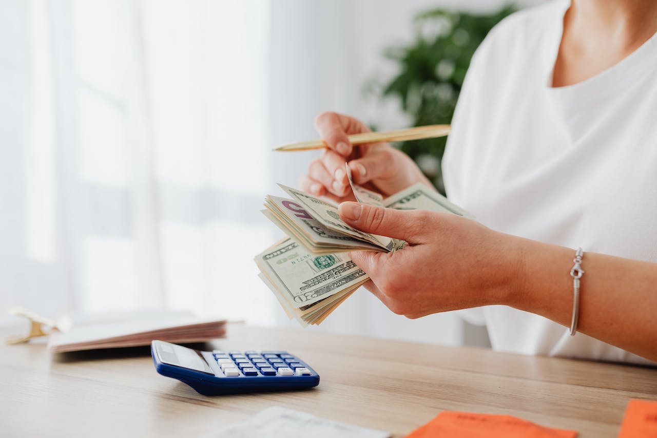 image of person counting money and a calculator on the table